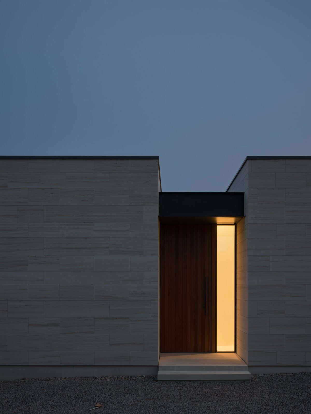 Warm light from a tall window beside a front door at dusk